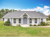 Charming single-story home featuring a well-manicured lawn, arched windows, and neutral-colored accents at 2590 Erena Dr, New Smyrna Beach, FL 32168