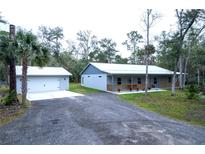 Charming single-story home featuring a detached garage and long gravel driveway at 2995 Ragis Rd, Edgewater, FL 32132