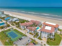 Expansive aerial view of beachfront condos featuring a pool, tennis court, and private beach access at 3001 S Atlantic Ave # 204, New Smyrna Beach, FL 32169