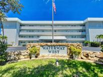 Exterior view of the Waterway West condo building with manicured landscaping and an American flag flying high at 315 N Causeway # 405, New Smyrna Beach, FL 32169