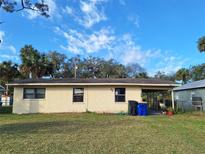 A single story home with a tan exterior and a simple covered porch overlooks a spacious backyard at 434 Palmetto St, Edgewater, FL 32132