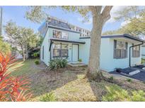 Charming light blue home with dark trim and a well-kept lawn with a large tree in the front at 49 Jacaranda Cay Ct # 49, New Smyrna Beach, FL 32169