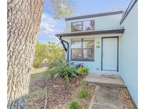 Charming light blue home with a white front door, complemented by lush, tropical landscaping at 49 Jacaranda Cay Ct # 49, New Smyrna Beach, FL 32169