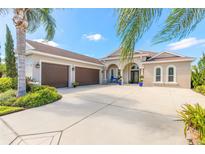 Stunning beige stucco home with a three-car garage, arched entry, and beautiful tropical landscaping at 512 Romdini St, New Smyrna Beach, FL 32168