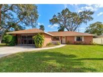 Charming single-story red brick home features a manicured lawn and mature shade trees at 704 Hillville Dr, Port Orange, FL 32127