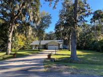 Charming single-story home featuring a lush green lawn, mature trees, and a cozy front porch at 2380 Captain Butler Trl, New Smyrna Beach, FL 32168