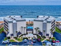 Aerial view of a beachfront condo complex, showcasing the building's architecture, pool, and ocean views at 1275 Ocean Shore Blvd # 5050, Ormond Beach, FL 32176