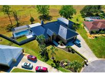 Stunning aerial view of home featuring lush landscaping, a spacious driveway, and screened in pool at 1948 Spruce Creek Lndg, Port Orange, FL 32128