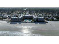 Stunning aerial view of beachfront condo building with pool, sandy beach, and lush landscaping at 2401 S Atlantic Ave # A604, New Smyrna Beach, FL 32169