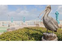 Pelican statue overlooking outdoor lounge area with tables, chairs, and umbrellas at 2401 S Atlantic Ave # D301, New Smyrna Beach, FL 32169