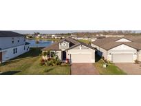 Inviting home with a brick driveway and attached two-car garage, complemented by lush landscaping and a view of the pond at 2820 Neverland Dr, New Smyrna Beach, FL 32168