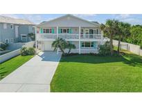 Charming two-story home with double balconies, a well-manicured lawn, and a long concrete driveway at 4624 Van Kleeck Dr, New Smyrna Beach, FL 32169