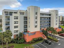 Multi-story condo complex with colorful exterior, lush landscaping and ample parking on a sunny day at 5300 S Atlantic Ave # 3-301, New Smyrna Beach, FL 32169