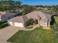 Beautiful tan home with a well-manicured lawn, a three-car garage and mature landscaping near the golf course at 6456 Cypress Springs Pkwy, Port Orange, FL 32128