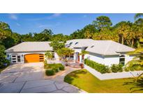 Stunning exterior view of a one-story home showcasing meticulous landscaping and a three-car garage at 725 Ingham Rd, New Smyrna Beach, FL 32168