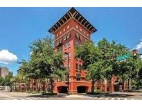 Exterior showcases a brick building featuring unique architecture and lush green trees at 911 N Orange Ave # 528, Orlando, FL 32801