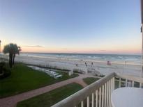 Beach view from balcony with palm trees, lawn furniture, and the ocean in the background at 111 N Atlantic Ave # A219, New Smyrna Beach, FL 32169