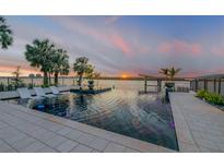 Stunning waterfront infinity pool with lounge chairs, fire feature, and picturesque sunset views over the water at 1194 N Peninsula, New Smyrna Beach, FL 32169