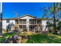 Condo with screened porches and wooden stairs in a grassy area with trees under a clear blue sky at 1600 Big Tree Rd # I2, South Daytona, FL 32119