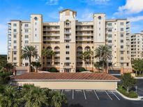 Elegant multi-story condo building with balconies, a tile roof, and palm trees under a bright, clear blue sky at 261 Minorca Beach Way # 606, New Smyrna Beach, FL 32169