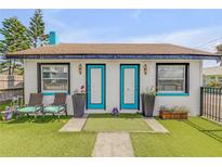 Charming home featuring turquoise door frames, manicured lawn and welcoming outdoor seating at 301 N Cooper St, New Smyrna Beach, FL 32169