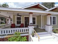 Charming front porch featuring red chairs, ceiling fans, and stylish columns, perfect for relaxing at 303 Washington St, New Smyrna Beach, FL 32168