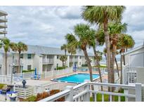 Resort pool area surrounded by palm trees, white fencing and community buildings at 4225 S Atlantic Ave # 2150, New Smyrna Beach, FL 32169