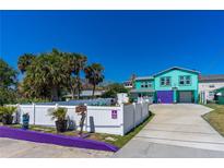 Charming two-story coastal home with colorful exterior, white fencing, and mature landscaping at 519 Mobile Ave, Daytona Beach, FL 32118