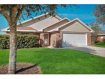 Charming one-story home featuring a well-manicured lawn, a brick facade, and a two-car garage at 549 Coral Trace Blvd, Edgewater, FL 32132
