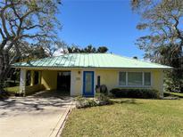 Charming yellow home with a green metal roof, well-maintained lawn, and blue trim accents at 630 Yupon Ave, New Smyrna Beach, FL 32169