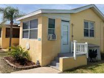 Charming home exterior featuring a small porch, palm trees, and a bright yellow facade at 835 E 24Th Ave # 111, New Smyrna Beach, FL 32169