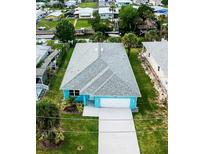 Aerial view of a bright blue house with a well-manicured lawn and a waterway nearby at 113 Douglas St, Edgewater, FL 32141