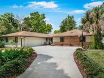 Charming single-story ranch-style home featuring a large driveway, mature trees, and well-maintained landscaping at 56 Live Oak Ln, New Smyrna Beach, FL 32168