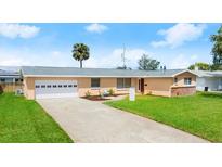 Charming single-story home features a well-maintained lawn, a two-car garage, and a classic concrete driveway at 121 Ellicott Dr, Ormond Beach, FL 32176