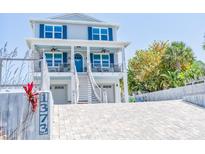 Two-story home with blue shutters and a charming front porch with seating and a brick driveway at 1373 N Atlantic Ave, New Smyrna Beach, FL 32169