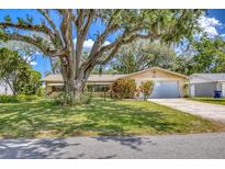 Charming single-story home with a well-manicured lawn, mature landscaping, and attached garage at 1855 Pine Tree Dr, Edgewater, FL 32141