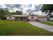 Charming single-story home with tan stucco and stone accents, lush lawn and inviting curb appeal at 1868 Pine Tree Dr, Edgewater, FL 32141
