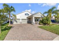 Beautiful two-story home with a brick driveway, palm trees, and a two-car garage at 220 Venetian Palms Blvd, New Smyrna Beach, FL 32168