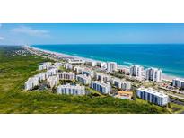 Expansive aerial view of a beachfront condo community with ocean views, lush greenery, and easy beach access at 5300 S Atlantic Ave # 20-507, New Smyrna Beach, FL 32169