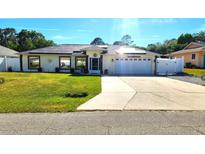 Charming single-story home featuring a well-manicured lawn, solar panels, and an attached two-car garage at 2820 Tamarind Dr, Edgewater, FL 32141