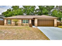 Charming single-story home featuring an attached garage, brick accents and manicured landscaping at 1119 Wild Oak Ter, Deland, FL 32720