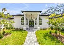 Stunning white stucco home with arched windows, black trim, and meticulously landscaped front yard at 1371 Melonie Trl, New Smyrna Beach, FL 32168