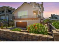 Beautiful two-story home with a balcony, lush landscaping, and a brick wall in a coastal community at 6260 S Atlantic Ave, New Smyrna Beach, FL 32169