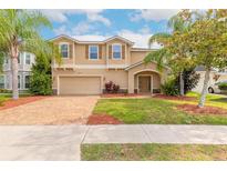 Charming two-story home with a brick driveway, well-manicured lawn, and beautiful landscaping at 6950 Vintage Ln, Port Orange, FL 32128