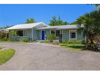 Charming single story home with a metal roof, lush landscaping and a large driveway at 913 Palmetto St, New Smyrna Beach, FL 32168