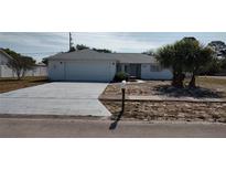 Charming single-story home featuring a white brick facade, well-manicured lawn, and an attached two-car garage at 1077 Willow Wood Dr, Port Orange, FL 32129