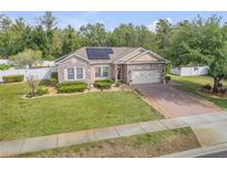Charming single-story home boasting a stone facade, solar panels, brick driveway, and manicured landscaping at 115 Los Arbor Dr, Deland, FL 32724