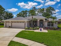 Charming single-story home with a three-car garage, lush lawn, and tropical landscaping at 1156 Rivercrest Ct, Port Orange, FL 32128