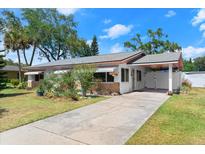 Charming single-story home with well-maintained lawn, carport, and mature trees under a bright blue sky at 1851 Needle Palm Dr, Edgewater, FL 32141