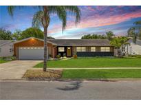 Charming single-story home with a well-manicured lawn and a colorful sunset backdrop at 2548 E Compton St, Orlando, FL 32806